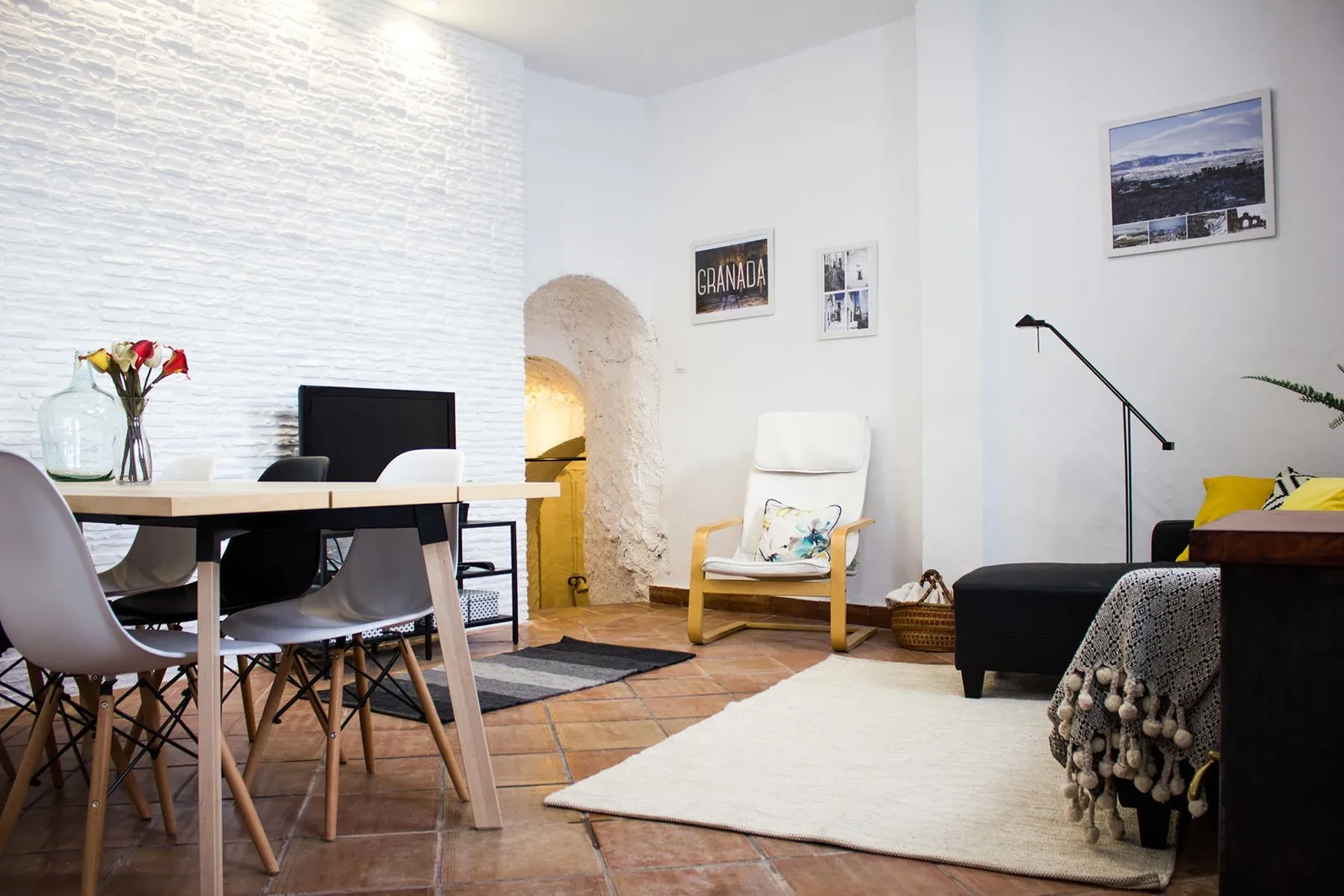 Salón con mesa de comedor, sofá y alfombra bajo los techos encalados