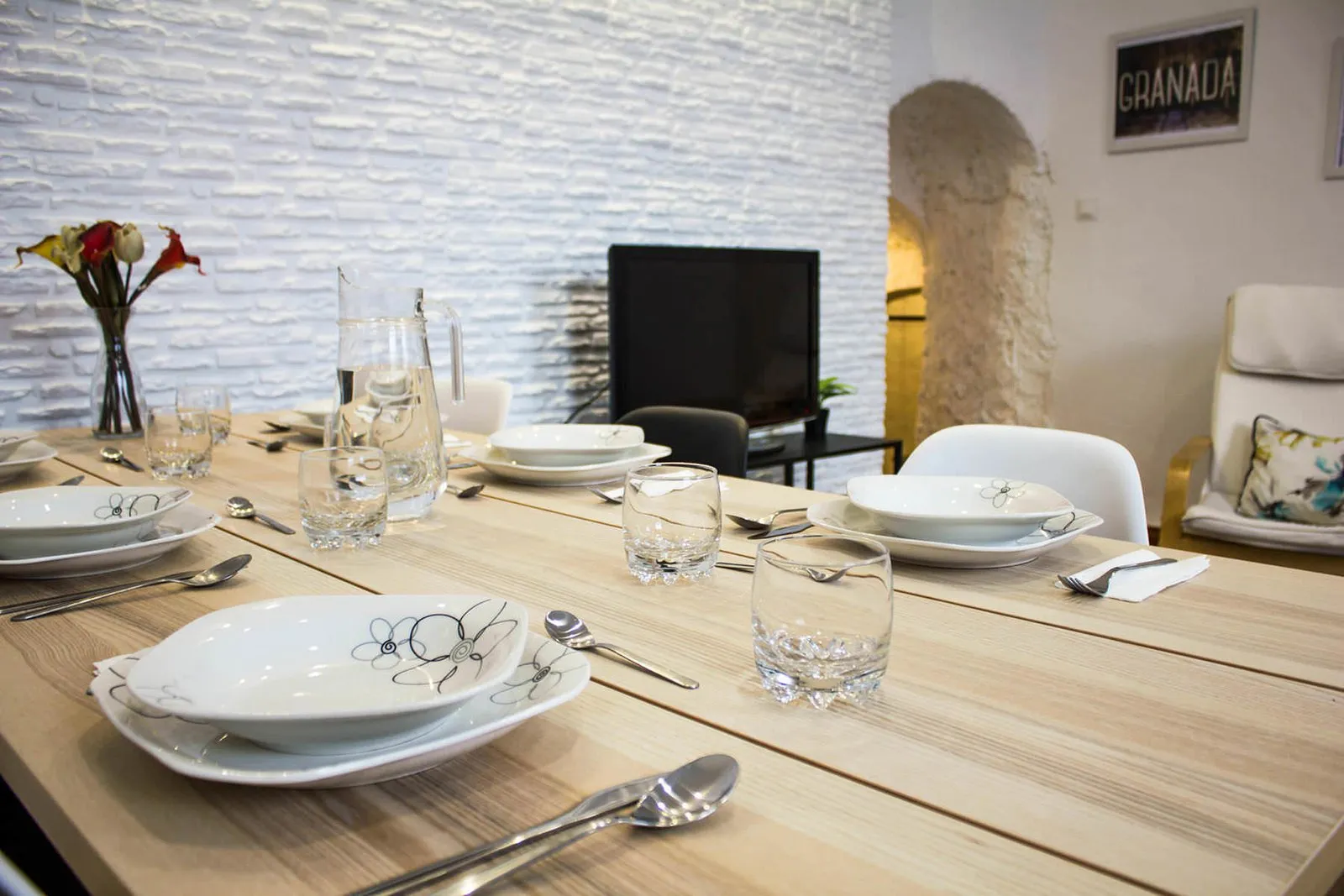 Detalle de la mesa puesta con platos, copas y flores
