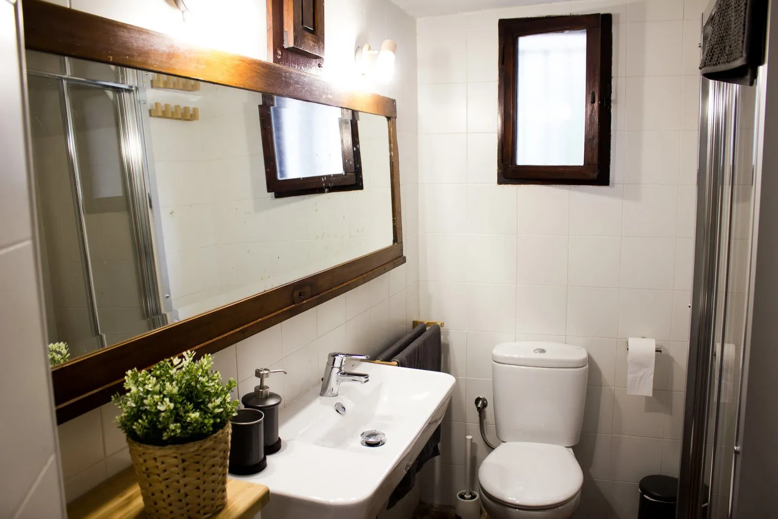 Vista general del baño con espejo, lavabo e inodoro