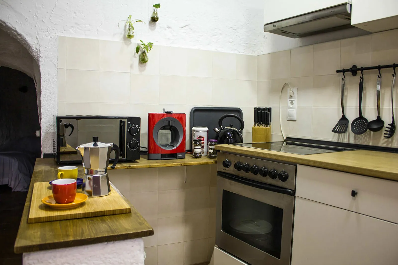 Cocina con microondas, tostadora y utensilios colgados