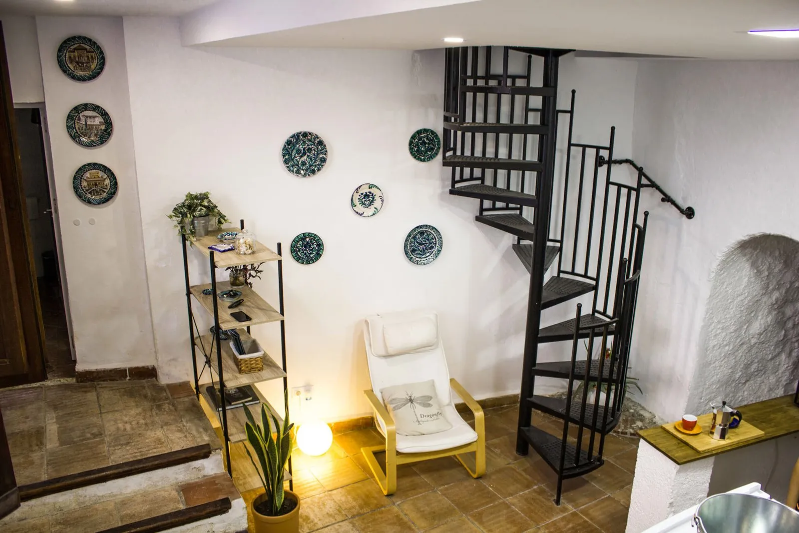 Entrada a la cocina con escalera de caracol y platos de cerámica en la pared