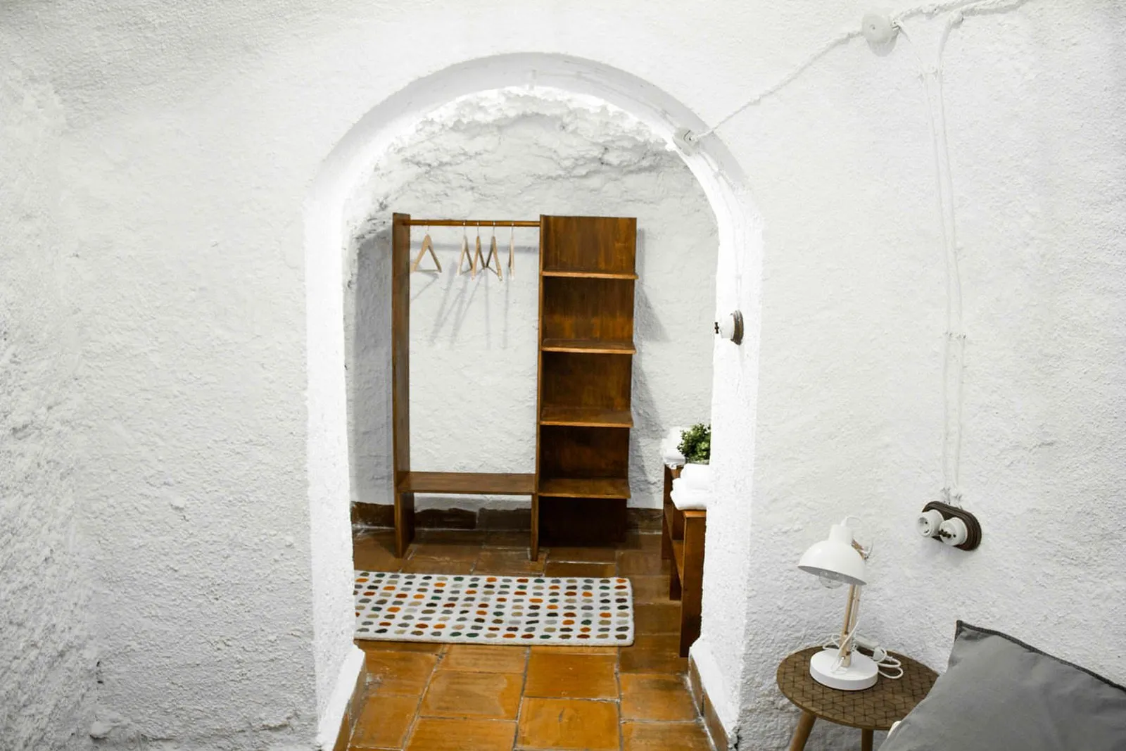 Cama de matrimonio con cojines grises y sillón de madera tallada