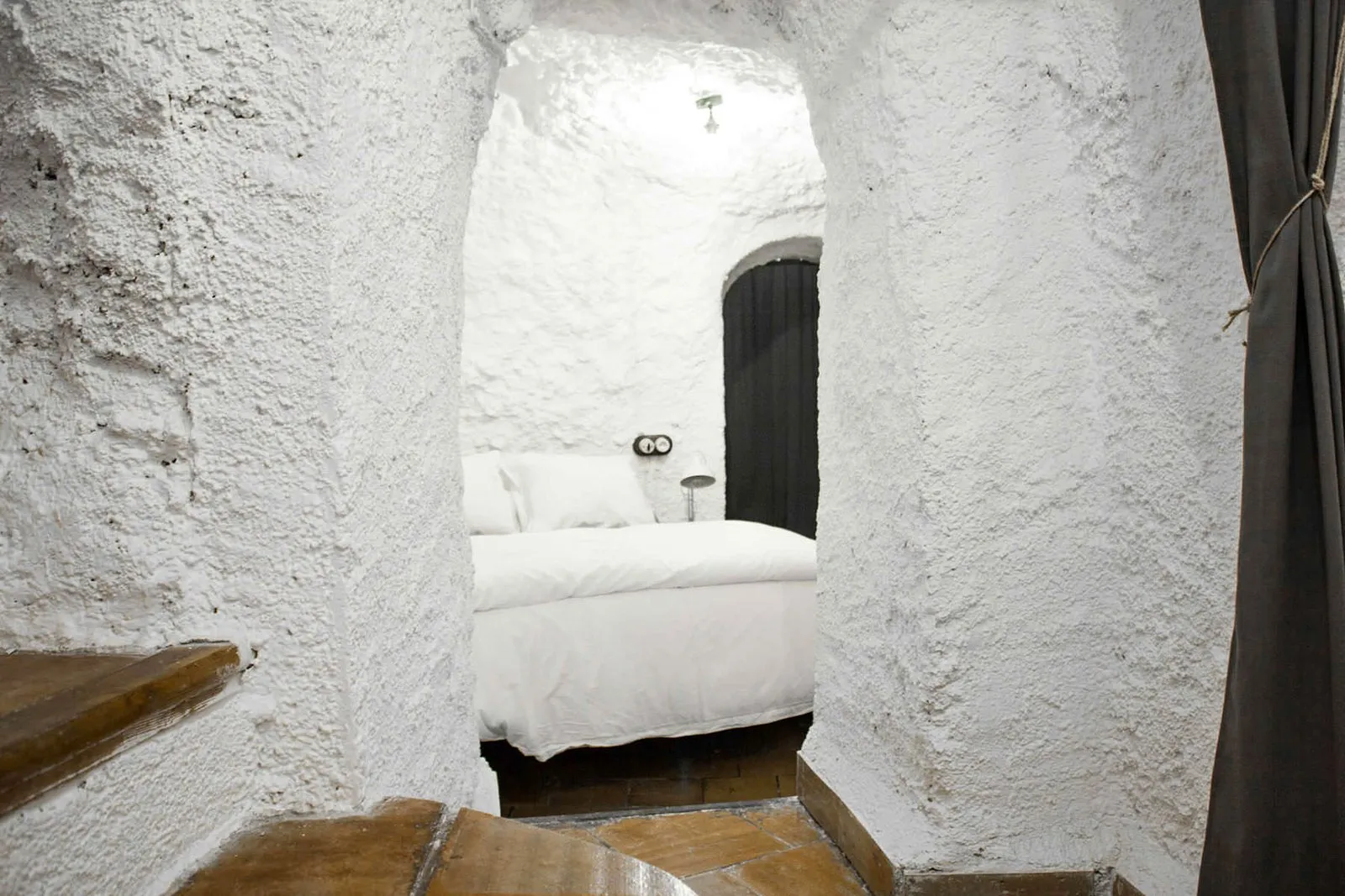 Cama individual grande al fondo de un pasillo excavado en la roca