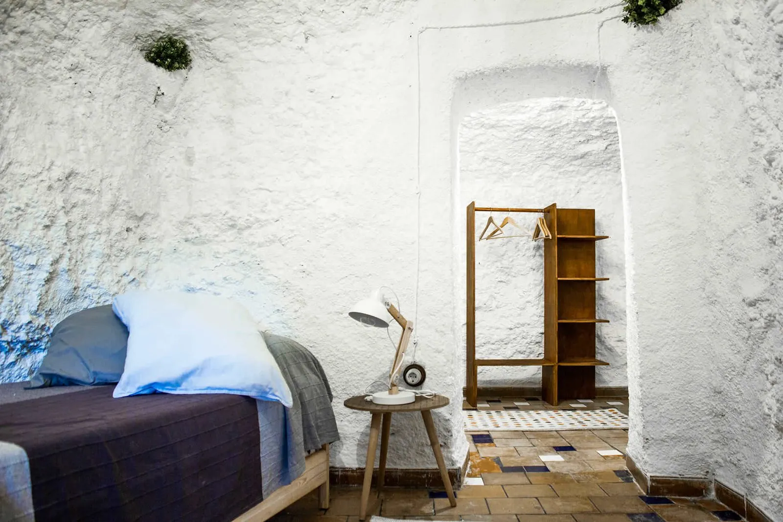 Dormitorio con cama individual y estantería de madera al fondo