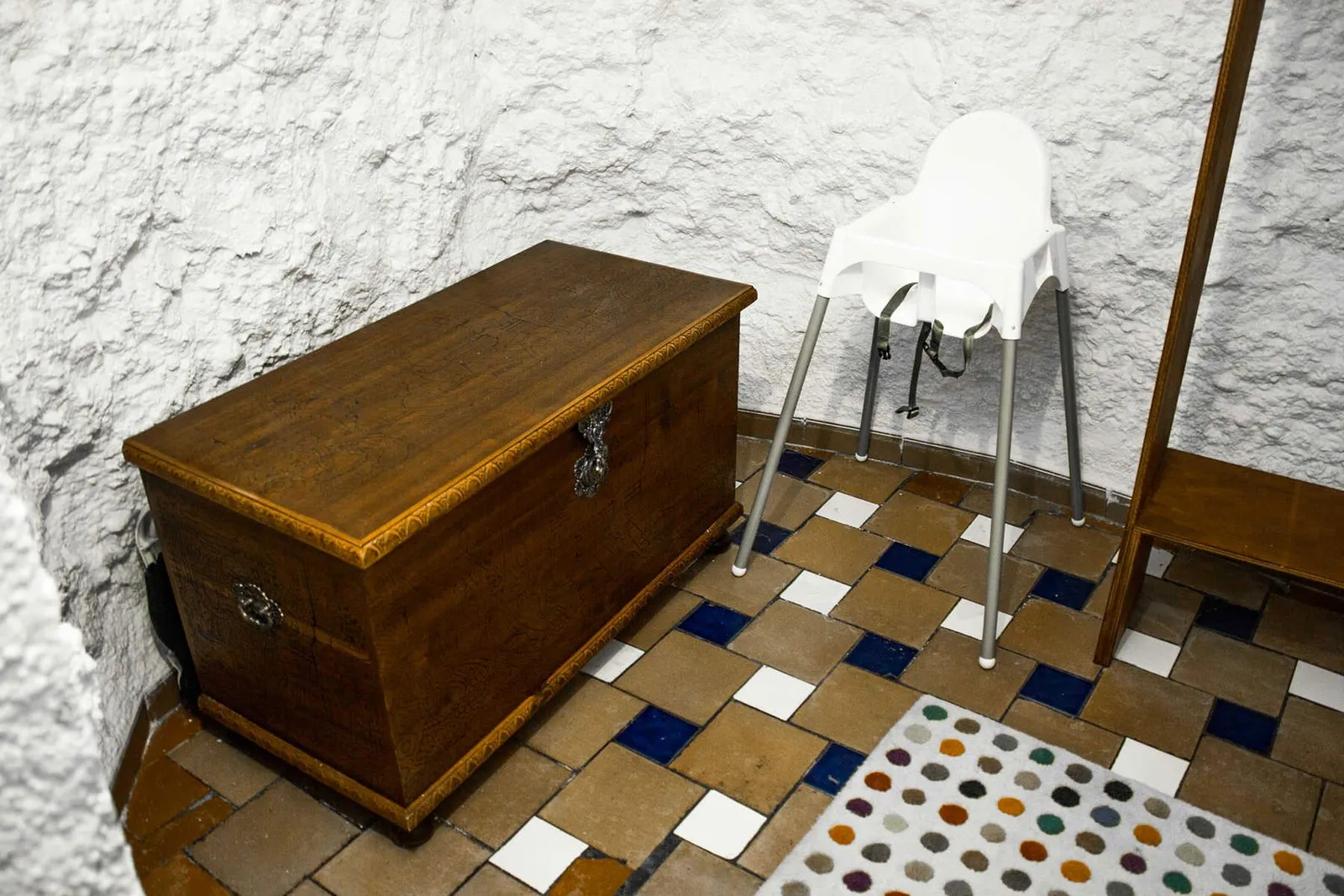 Vestidor con baúl de madera, trona y suelo de azulejos de colores
